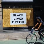 A biker rides by a sign that reads: Black Lives Matter